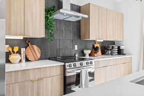 Een moderne keuken met houten kastjes, een fornuis, een oven en een afzuigkap.