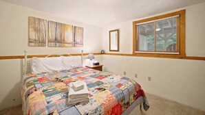 Un dormitorio con cama, mesita de noche, lámpara, ventana con persianas y decoración en la pared.