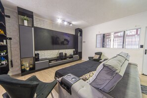 Een moderne slaapkamer met een bed, een bank, een televisie en inbouwkasten.