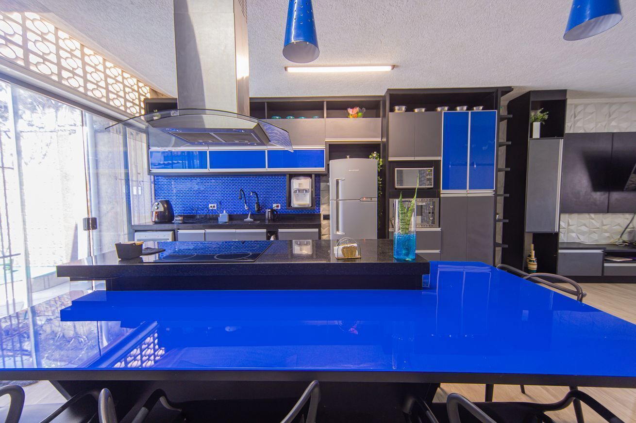 A modern kitchen with blue countertops, a central island, and a large window.