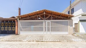 Una entrada protegida con un portón metálico, techo de tejas y un camino pavimentado.