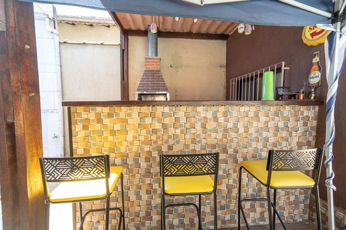 An outdoor patio with mosaic tile walls, a brick chimney, and metal chairs with yellow cushions.