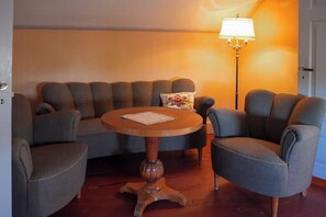 A room with a round wooden table, a sofa, and a floor lamp. - Authentic 1800s cottage in Småland (Svenstorp)