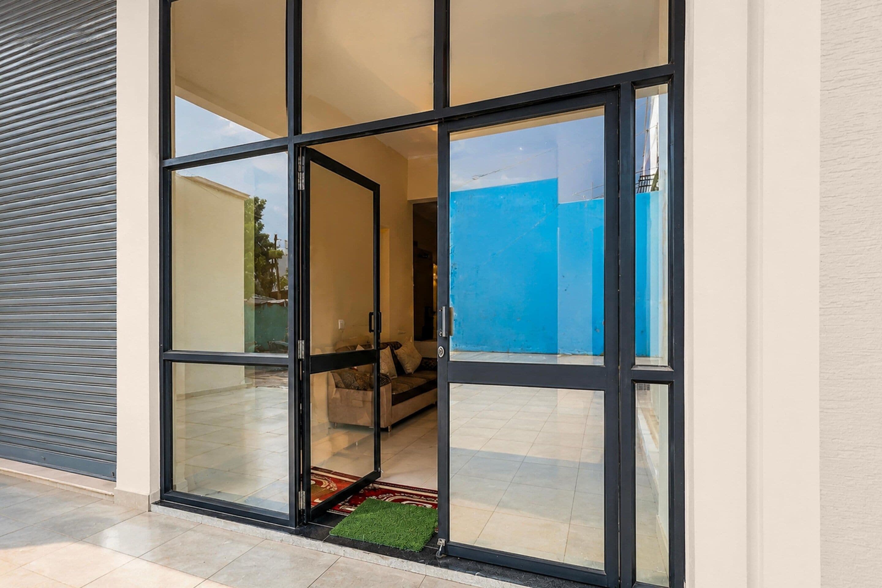 A modern building entrance with a glass door and a view of an interior living area.