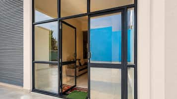 A modern building entrance with a glass door and a view of an interior living area.