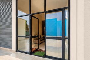 A modern building entrance with a glass door and a view of an interior living area. - Classic Golden Retreat Hotel (Anand)