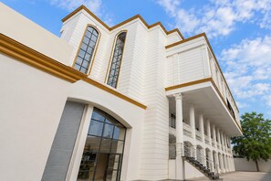 A building with a white facade, large windows, and a covered entrance with columns. - Classic Golden Retreat Hotel (Anand)