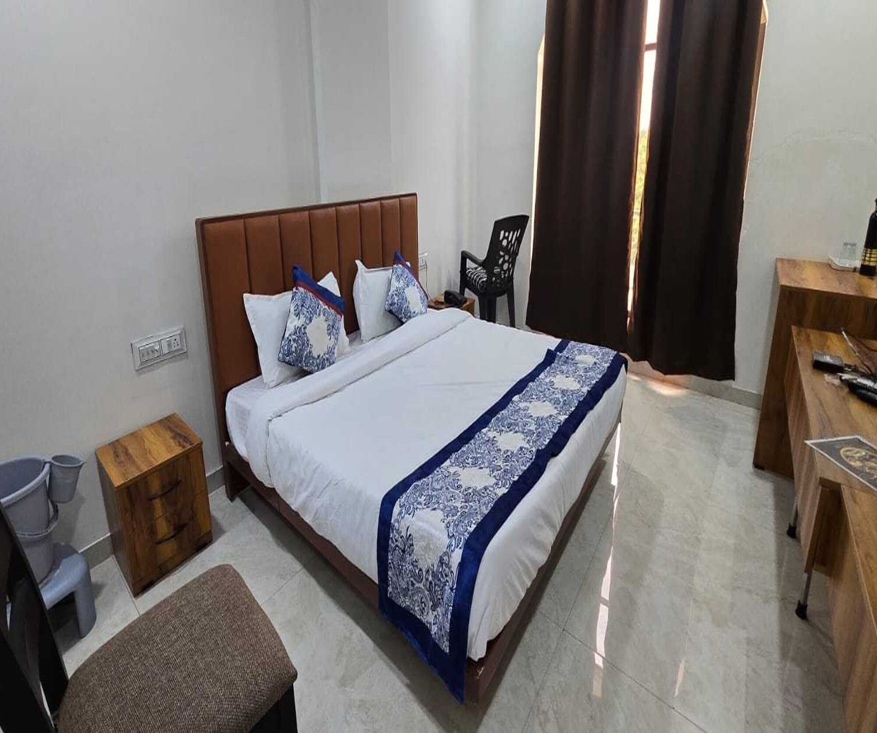 A hotel room with a bed, bedside table, chair, and a desk.