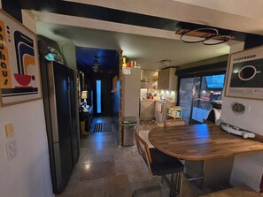 Een keuken met een houten tafel en stoelen, een koelkast en een raam met uitzicht.