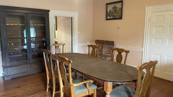 Comedor con una gran mesa de madera rodeada de seis sillas, un aparador de madera oscura con puertas de cristal y paredes de color crema.