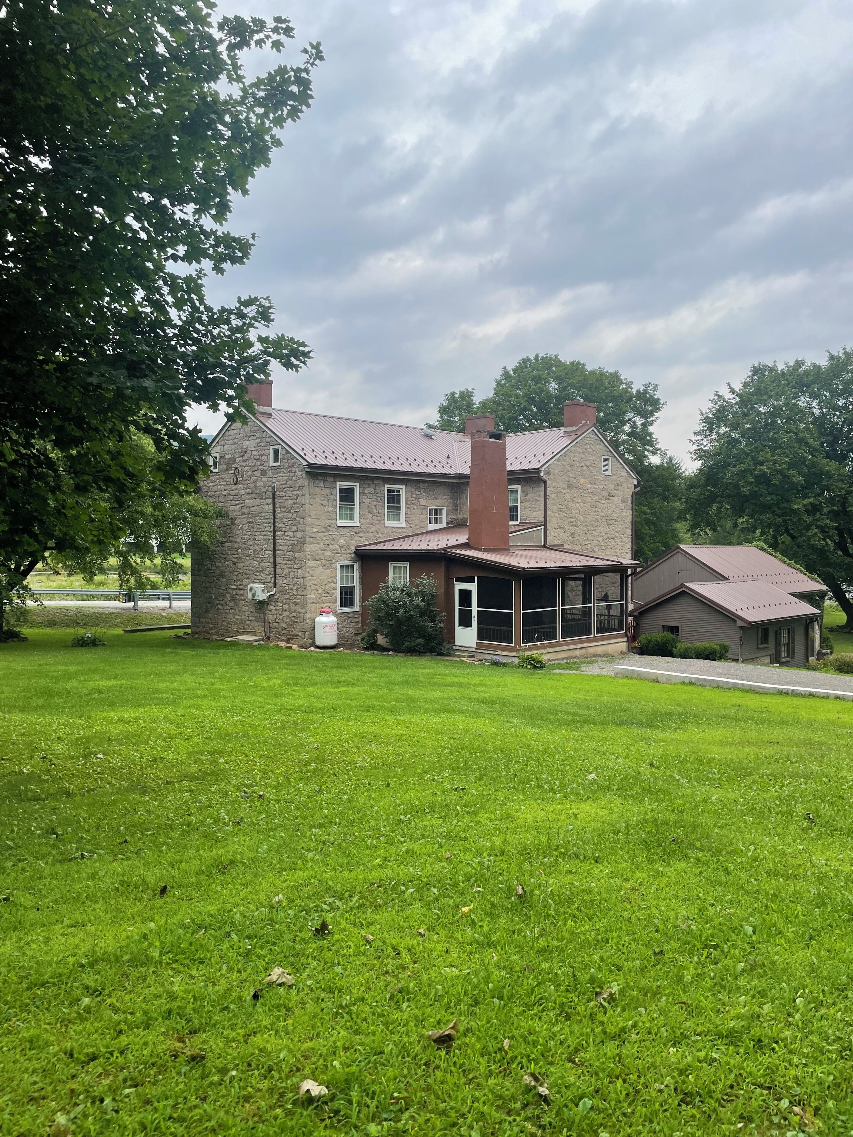 A two-story stone house with a covered porch and a small attached garage.