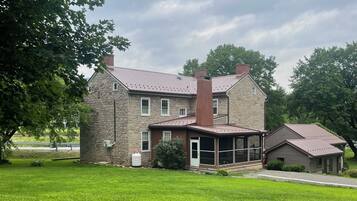 A two-story stone house with a covered porch and a small attached garage.