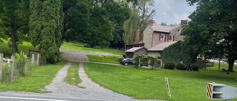 A residential street with a house, a driveway, and a road with double yellow lines.