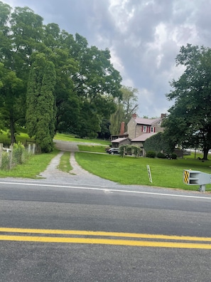 A residential street with a house, a driveway, and a road with double yellow lines.