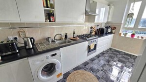 A compact kitchen with a washing machine, a sink, and a stove. - Bright and spacious 1 bedroom flat near Warren Street. Perfect to explore London (London)