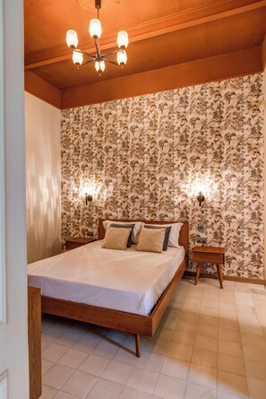 Une chambre à coucher avec un lit en bois, un papier peint à motifs floraux et un lustre.