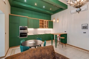 Une cuisine moderne avec des meubles de couleur verte, une table à manger en bois et des chaises turquoise.