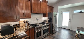 A kitchen with wooden cabinets, a stainless steel stove, a refrigerator, and a window with a view. - Waterfront Lake House Retreat — Sleeps 12 _ Private Dock _ Upgraded Interior (Brownwood)