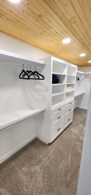 A walk-in closet with white shelving units, hanging space, and drawers. - Waterfront Lake House Retreat — Sleeps 12 _ Private Dock _ Upgraded Interior (Brownwood)