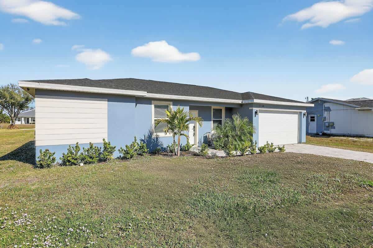 A single-story residential building with a flat roof, a front garage, and a small front yard with landscaping.