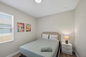 Ein Schlafzimmer mit Bett, Nachttisch, Lampe und Bildern an der Wand.