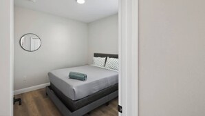 Ein Schlafzimmer mit einem Einzelbett, einem runden Spiegel an der Wand und einer Deckenleuchte.