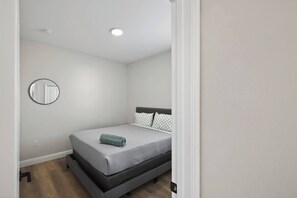 A bedroom with a single bed, a round mirror on the wall, and a ceiling light. - Beautiful 4/2 Oasis: Beaches Nearby | w/ King Bed (Englewood)