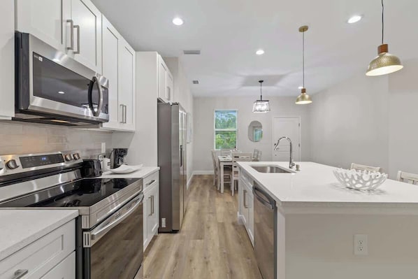 A modern kitchen with stainless steel appliances, a central island, and pendant lighting.