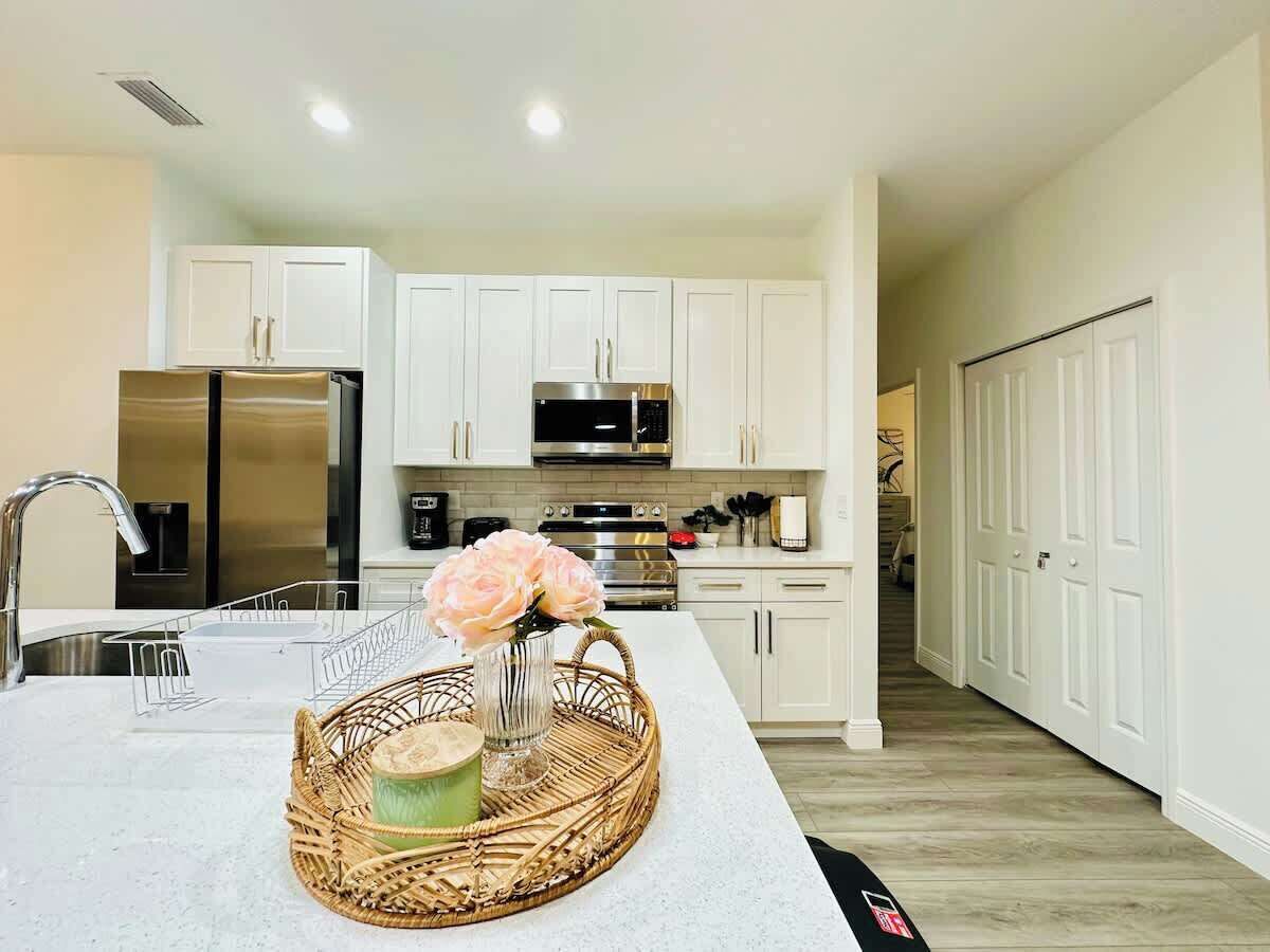 A modern kitchen with white cabinets, stainless steel appliances, and a central island with a vase of flowers.