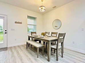 A dining area with a table set for four, a bench, and a round mirror on the wall. - Elegant, Modern And New House (Port Charlotte)