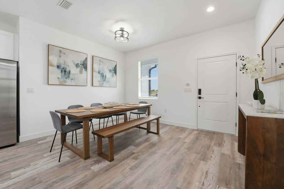 A modern kitchen with a dining area, featuring a wooden table, chairs, and a bench.