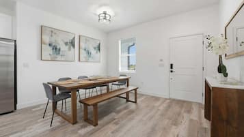 A modern kitchen with a dining area, featuring a wooden table, chairs, and a bench.