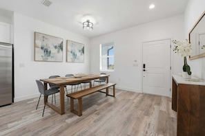 A modern kitchen with a dining area, featuring a wooden table, chairs, and a bench.