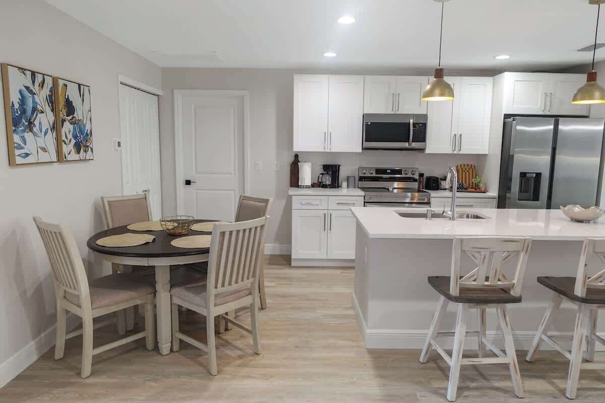 A modern kitchen with white cabinetry, stainless steel appliances, and pendant lighting.