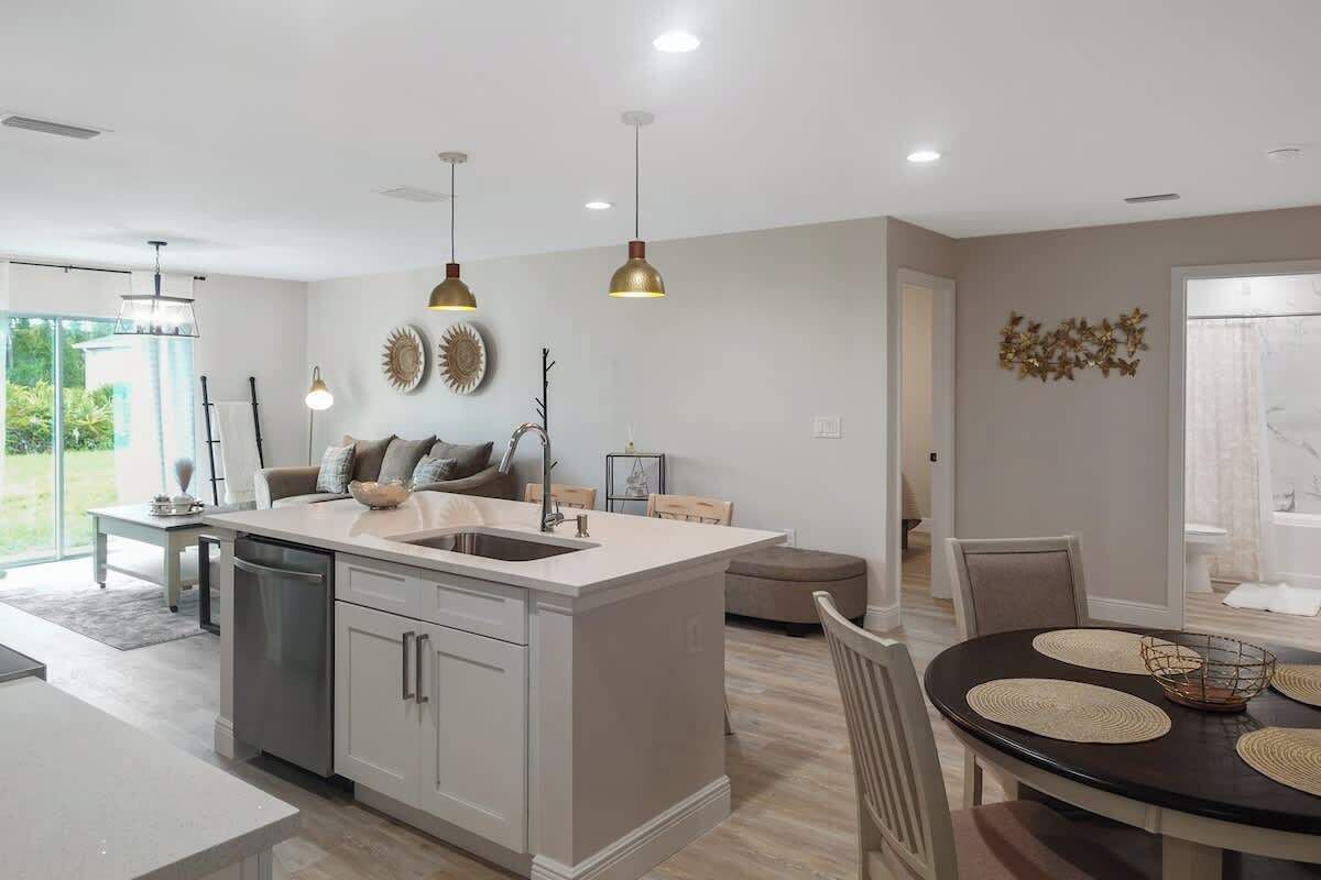 A modern kitchen with a central island, pendant lighting, and a dining area with a round table.
