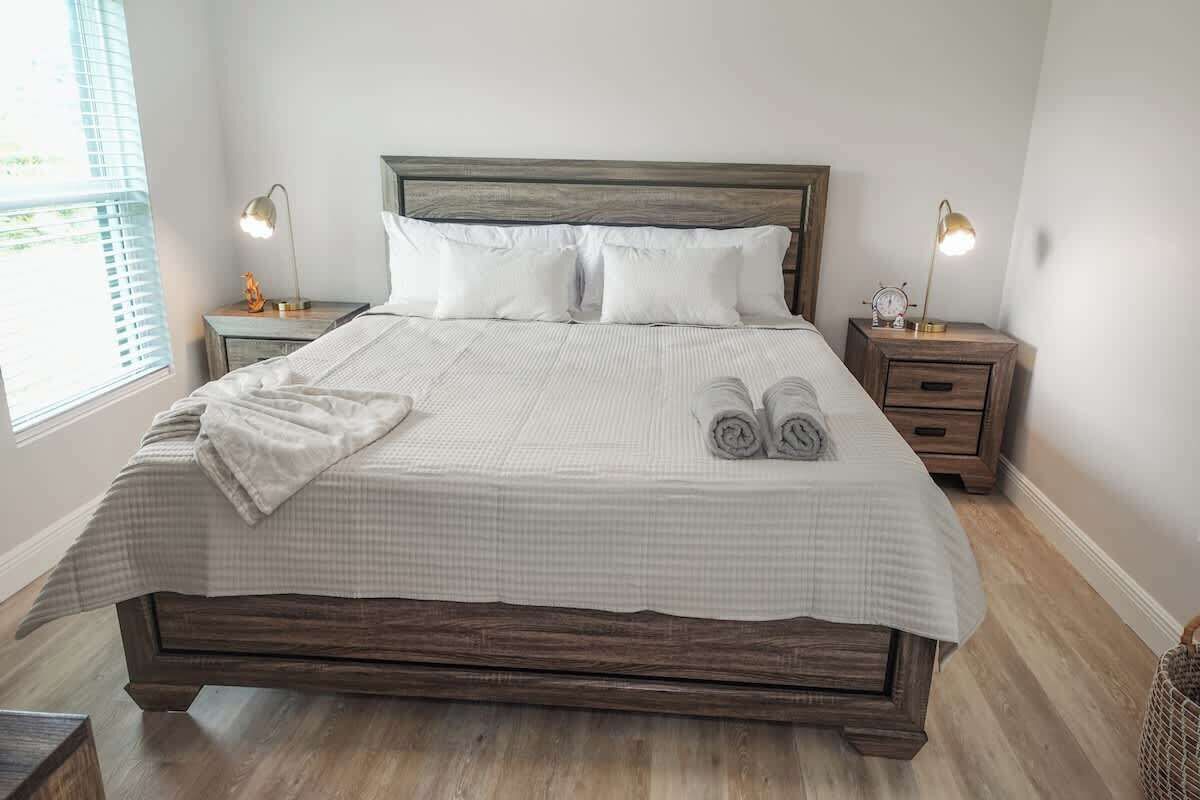 A neatly made bed with a checkered bedspread, two bedside lamps, and a wooden headboard.