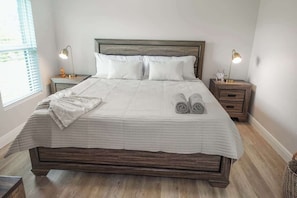 A neatly made bed with a checkered bedspread, two bedside lamps, and a wooden headboard. - Coastal Escape: New Luxury House (Port Charlotte)