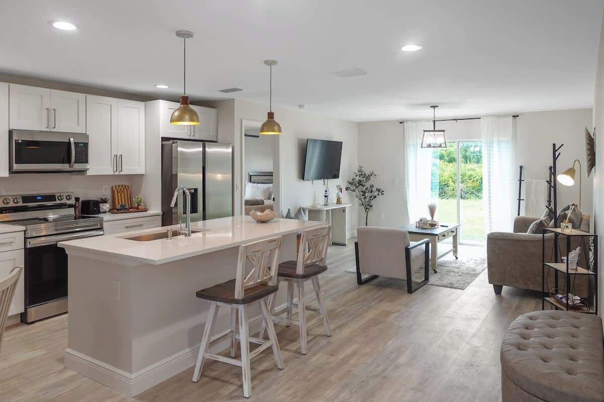 A modern kitchen with white cabinetry, stainless steel appliances, and a central island with bar stools.