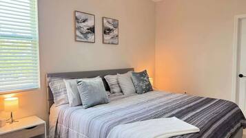 Une chambre à coucher comprenant un lit, une table de chevet et deux tableaux accrochés au mur.
