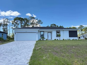 Een modern gelijkvloers huis met garage, voordeur en een kleine voortuin.