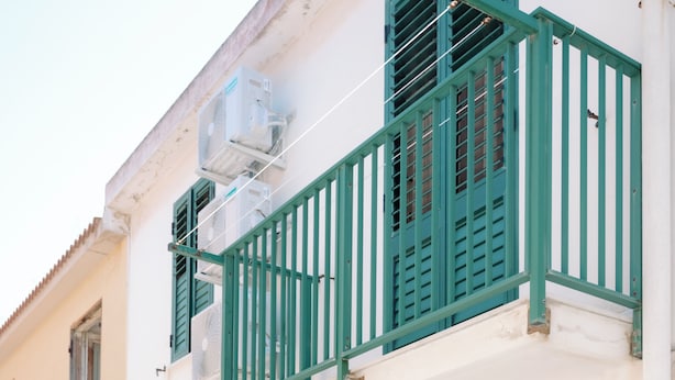 A building with a white facade, green shutters, and a balcony with a green railing.