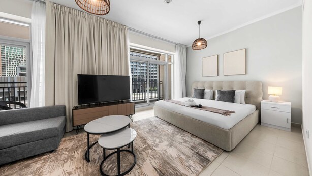 A modern hotel room with a large bed, a TV, a sofa, and a dining area. - Free Housekeeping Visits During Your Stay - Stayshort - Luxury Studio Apartment in Downtown With Balcony (Dubai)