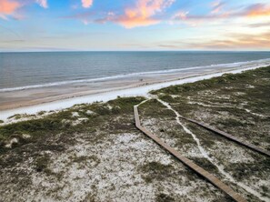 A beach with a wooden boardwalk leading to the shore, sandy dunes, and a calm sea under a partly cloudy sky. - Private Hot Tub | Dogs Welcome | Grill (Port St. Joe)