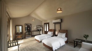 Habitación de hotel moderna con dos camas, un escritorio, una silla y una pequeña mesa con una planta.