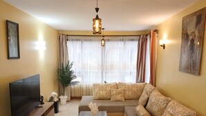 Un salon avec un canapé, une table basse, un téléviseur et une plante.