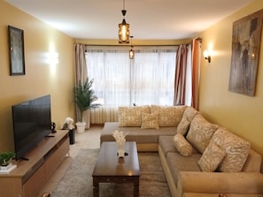 A living room with a sofa, a coffee table, a TV, and a plant. - The Terminal Residence (JWM9+X5X, Nairobi, Kenya)
