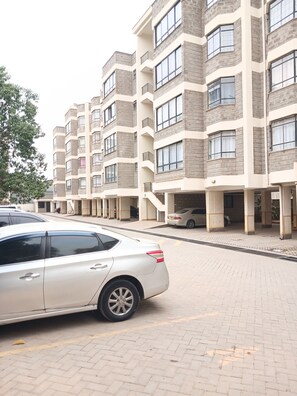 A multi-story residential building with a parking area in front.