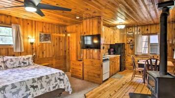 A cabin interior with a bed, kitchenette, dining area, and a fireplace.