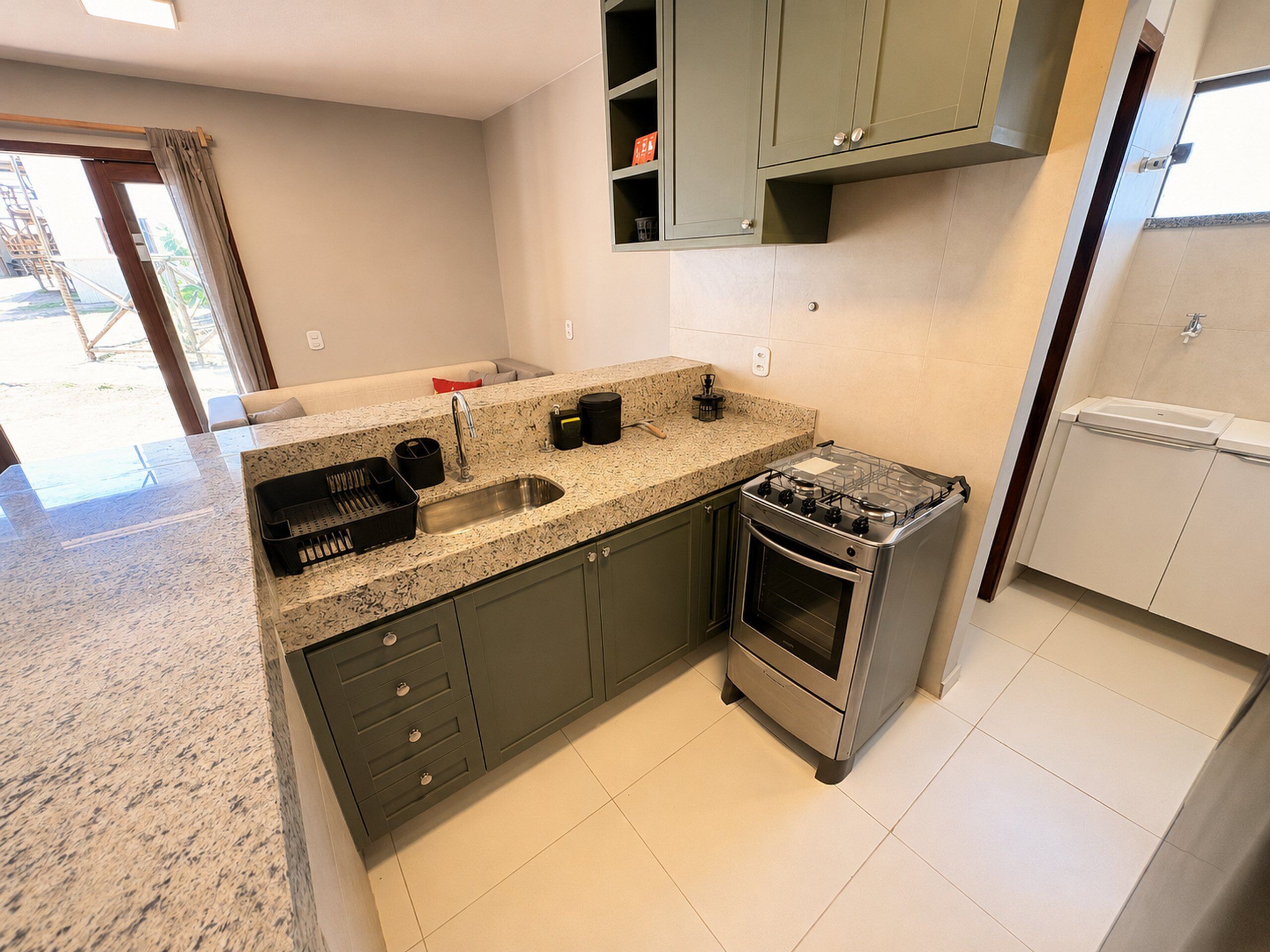 Una cocina con encimera de granito, electrodomésticos de acero inoxidable y armarios verdes.