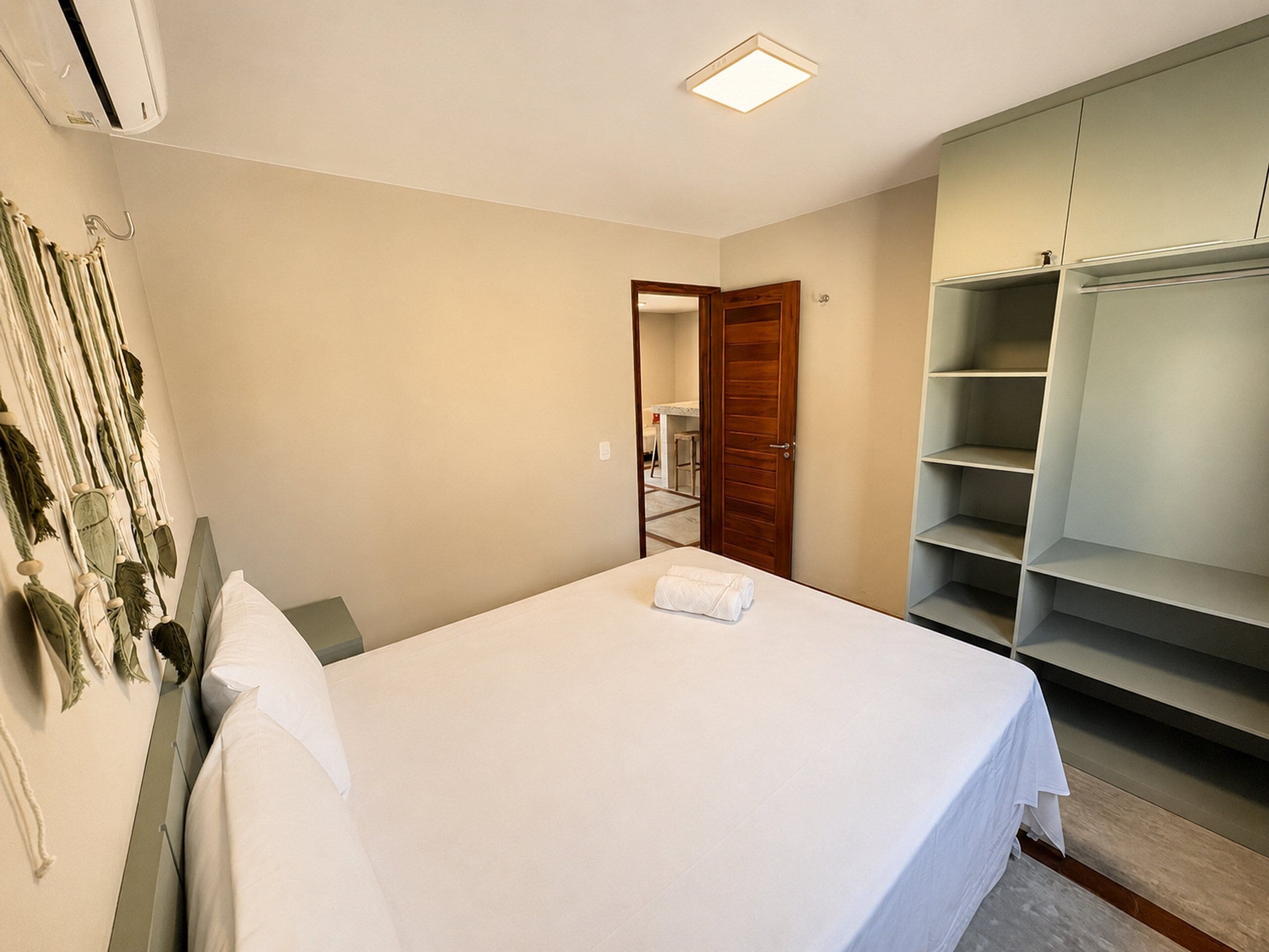 Um quarto com cama, guarda-roupa e ar-condicionado fixado na parede.